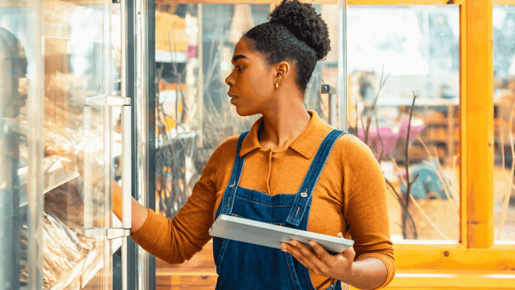 mulher segurando um tablet no Ponto de Venda analisando uma prateleira do supermercado